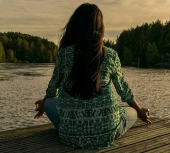 Bien-être mental : une personne, une femme méditant au bord de la rivière.