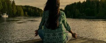 Bien-être mental : une personne, une femme méditant au bord de la rivière.
