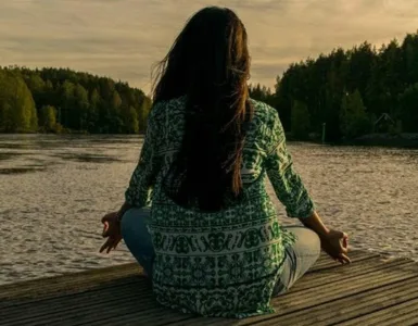 Bien-être mental : une personne, une femme méditant au bord de la rivière.