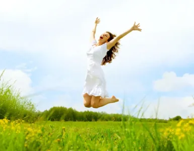 Alimentation anti-fatigue : image, photo d'une personne, une femme pleine d’énergie, en train de sauter dans un champ ensoleillé ou de sourire avec les bras ouverts.