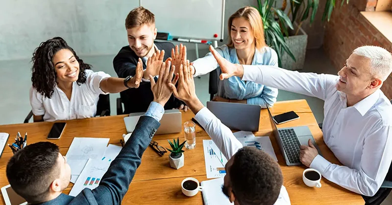 Image, photo d'un groupe de personnes, une équipe, hommes et femmes se tapant dans la main, ambiance positive et motivante.