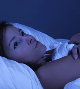 Insomnie : image d'une personne, une femme allongée dans son lit, les yeux grands ouverts, regardant le plafond.