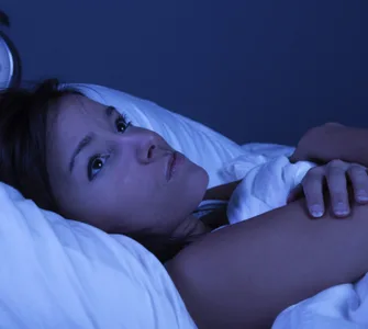 Insomnie : image d'une personne, une femme allongée dans son lit, les yeux grands ouverts, regardant le plafond.