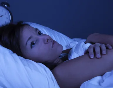 Insomnie : image d'une personne, une femme allongée dans son lit, les yeux grands ouverts, regardant le plafond.