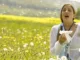 Les allergies : image, photo d'une personne, une femme éternuant dans un champ de fleurs au printemps.